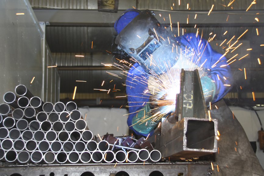 Labourer arc welding a sheet or piece of metal